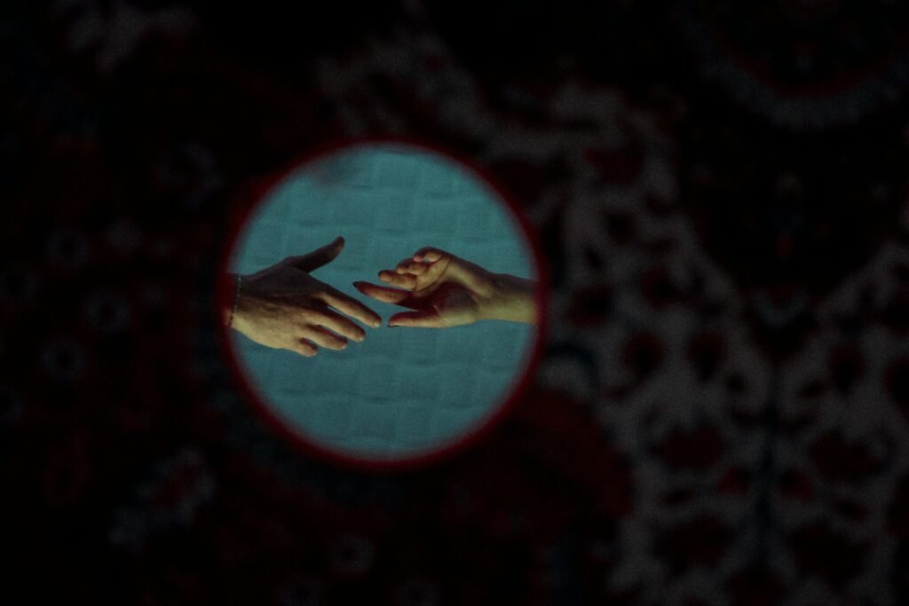 pexels-photo-17446772-17446772 Artistic close-up of two hands reaching towards each other against a patterned background.